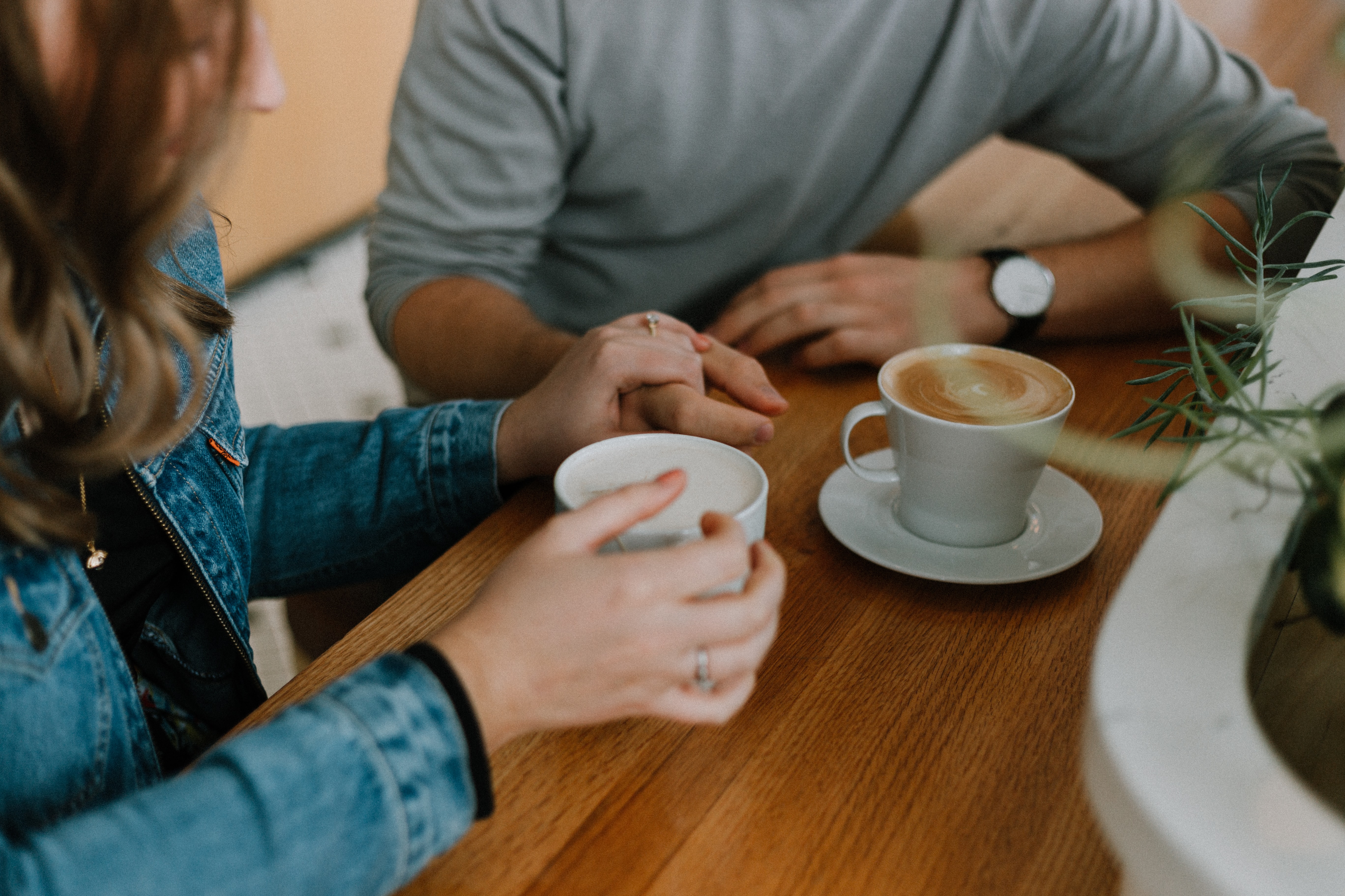 Two people having coffee together. One person is holding the hand of the other person.